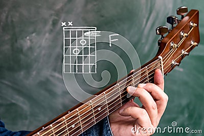 Man playing guitar chords displayed on a blackboard, Chord F Stock Photo