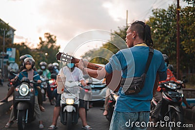 Man playing guitar at the traffic light intersection to collect some money for buying food Editorial Stock Photo