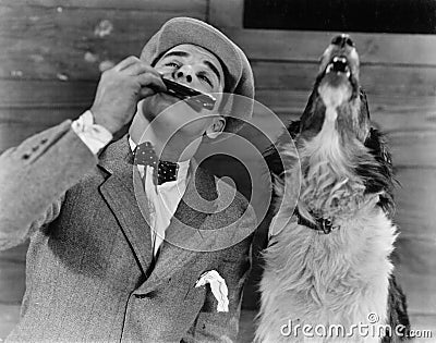 Man playing harmonica with howling dog Stock Photo