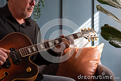 Man playing a vintage jazz guitar at home Stock Photo