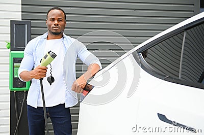 Man Plugging In Electric Car Outside Office In Car Park Charging Stock Photo