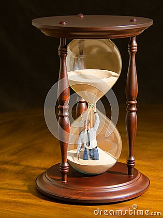 Man plugging hole inside hour glass trying to slow the flow of sand and stop time Stock Photo