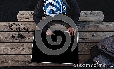 A man pointing finger on empty black paper, Travelers planning for a vacation trip on wooden table, top view Stock Photo