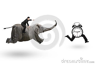 Man with pointing finger riding elephant running after alarm clock Stock Photo