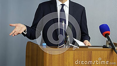 A man - a politician, businessman, official or lawyer gesticulates with his hands, speaking from the podium in front of Stock Photo