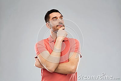 Man in polo t-shirt thinking over gray background Stock Photo