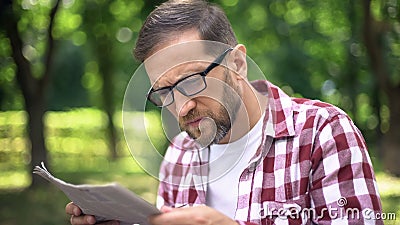 Man with poor sight trying to read newspaper in park, farsightedness, myopia Stock Photo