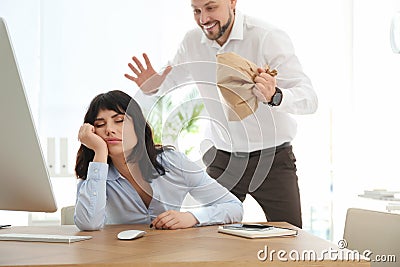 Man popping paper bag behind his sleeping colleague. April fool`s day Stock Photo