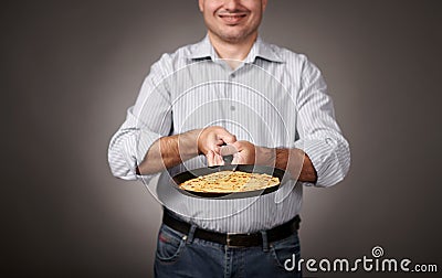 Man posing with a pancake in a pan, white shirt and pants, gray background, shallow depth of field, sharp pancake and blurred face Stock Photo