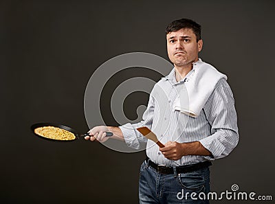Man posing with a pancake in a pan, white shirt and pants, gray background, surprised emotions Stock Photo