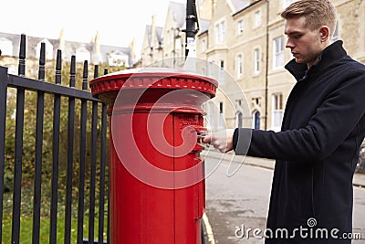 Man Posting Letter In Red British Postbox Stock Photo