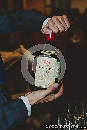 Man pouring alcohol from a bottle into a glass. Editorial Stock Photo