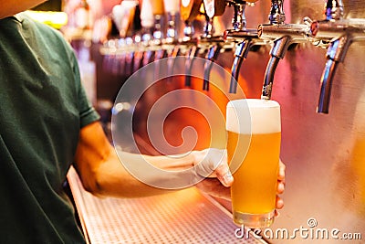 Man pouring craft beer from beer taps in frozen glass with froth. Selective focus. Alcohol concept. Vintage style. Beer craft Stock Photo