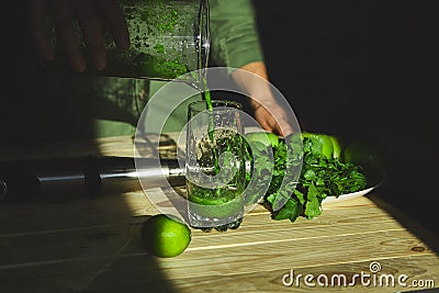Man pouring in glass healthy detox smoothie, cooking with blender with fresh fruits and greens spinach Stock Photo