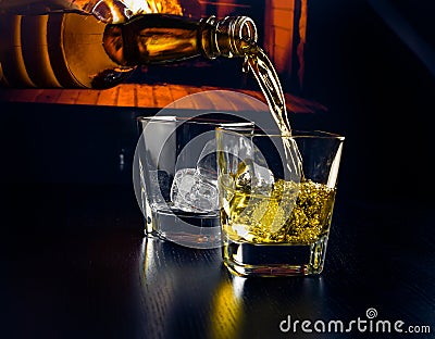 Man pouring glasses of whiskey with ice cubes in front of the fireplace Stock Photo