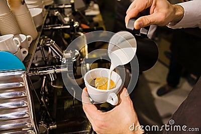 Man Pouring Milk into Coffee Making Espresso. Stock Photo