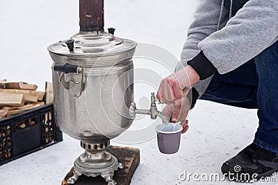 A man pours boiling water from a samovar during a winter picnic Stock Photo