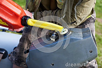 Man pours petrol into engine of fishing boat Stock Photo