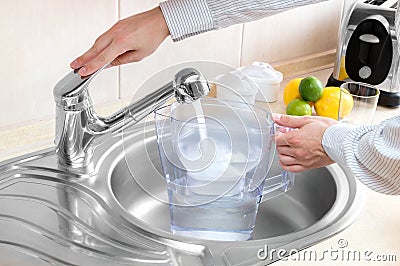 Man pours water into filter jug Stock Photo