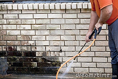 Man powerwashing mold of wall - DIY Stock Photo