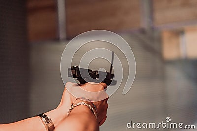 A man practices shooting a pistol in a shooting range while wearing protective headphones Stock Photo