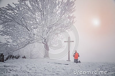 Man pray before the cross in winter nature. Christianity, faith, religion concept photo Stock Photo