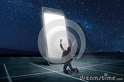 Man praying on his knees against large smartphone Stock Photo