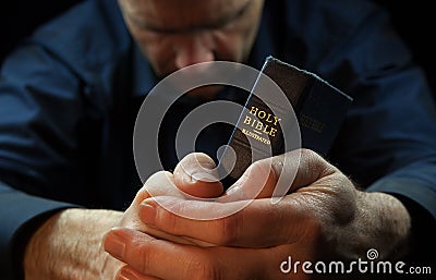 A Man praying holding a Bible. Stock Photo