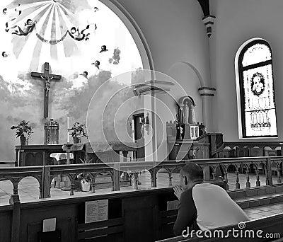 Man Praying inside a Religious Church with Beautiful Stained Glass and Cross Stock Photo