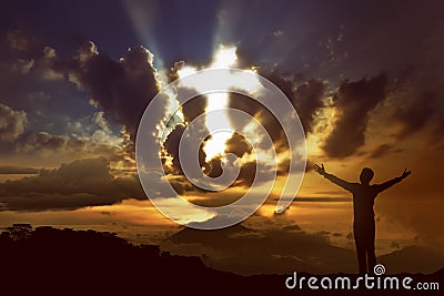Man praying to god with ray of light shaping cross on the sky Stock Photo