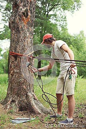 Man prepares the equipment fixes secures the rope to the tree Stock Photo