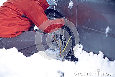 Man preparing car for travelling at winter day. Snow chains on the wheels of car snowy day Stock Photo