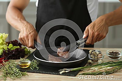 Man preparing delicious meat with fresh spices in kitchen Stock Photo