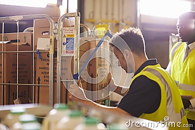 Man preparing roll cages for delivery, watched by supervisor Stock Photo