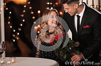 Man presenting roses to his beloved woman in restaurant at Valentine`s day dinner Stock Photo