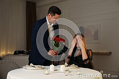 Man presenting roses to his beloved woman at romantic dinner Stock Photo