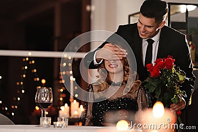 Man presenting roses to his beloved woman in restaurant at Valentine`s day dinner Stock Photo