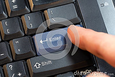 Man pressing a blue enter key on a laptop computer keyboard, hand finger object detail closeup, confirmation abstract concept, Stock Photo