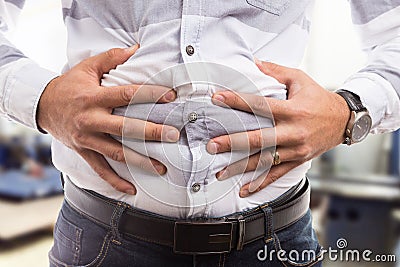 Man pressing bloated abdomen or belly as cramp flatulence problem. Stock Photo