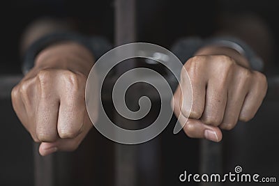 Man in prison hands of behind hold Steel cage jail bars, Male prisoners were severely strained in the dark prison, violence, Stock Photo