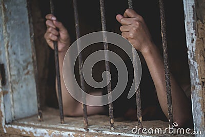 Man in prison hands of behind hold Steel cage jail bars, Male prisoners were severely strained in the dark prison, violence, Stock Photo