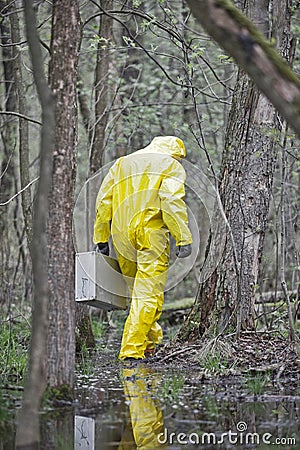 Man in professional uniform with silver suitcase walking in contaminated floods area Stock Photo