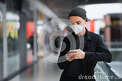 Man in protective mask with cell phone at a shopping centre or underground. Stock Photo