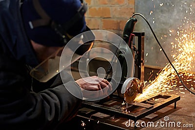 A man in a protective mask cuts metal on a machine tool Stock Photo