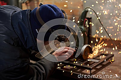 A man in a protective mask cuts metal on a machine tool Stock Photo