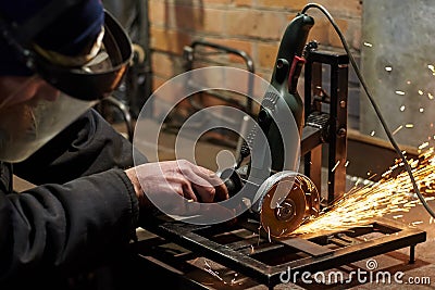 A man in a protective mask cuts metal on a machine tool Stock Photo