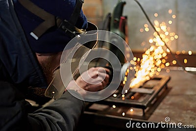 A man in a protective mask cuts metal on a machine tool Stock Photo