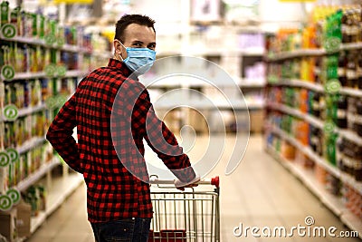 Man in protective mask shopping in supermarket pushing trolley during epidemic Stock Photo