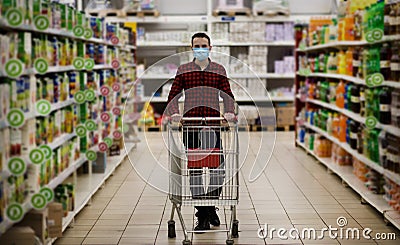 Man in protective mask shopping in supermarket pushing trolley during epidemic Stock Photo