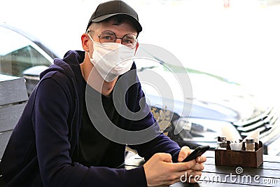 Man in protective mask sitting in empty cafe Stock Photo